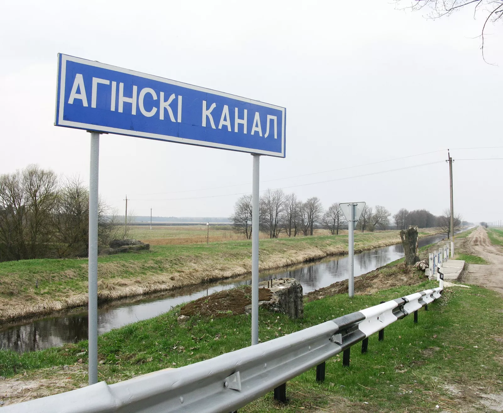 Табличка «Агінскі канал» біля вузького каналу серед полів
