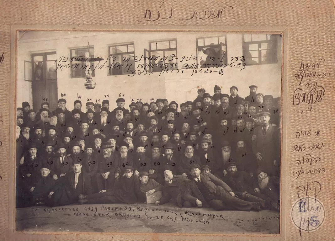 Велика групова фотографія учасників з’їзду рабинів у залі синагоги, частина людей у вікнах