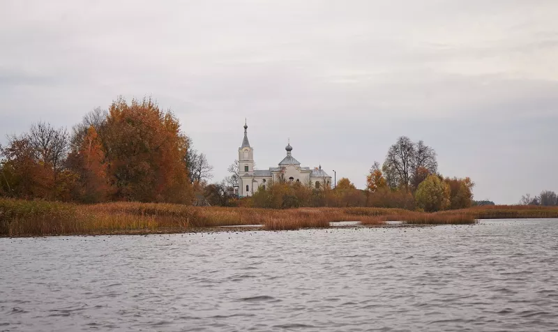 Білий храм у селі Нобель над водою серед осінніх дерев